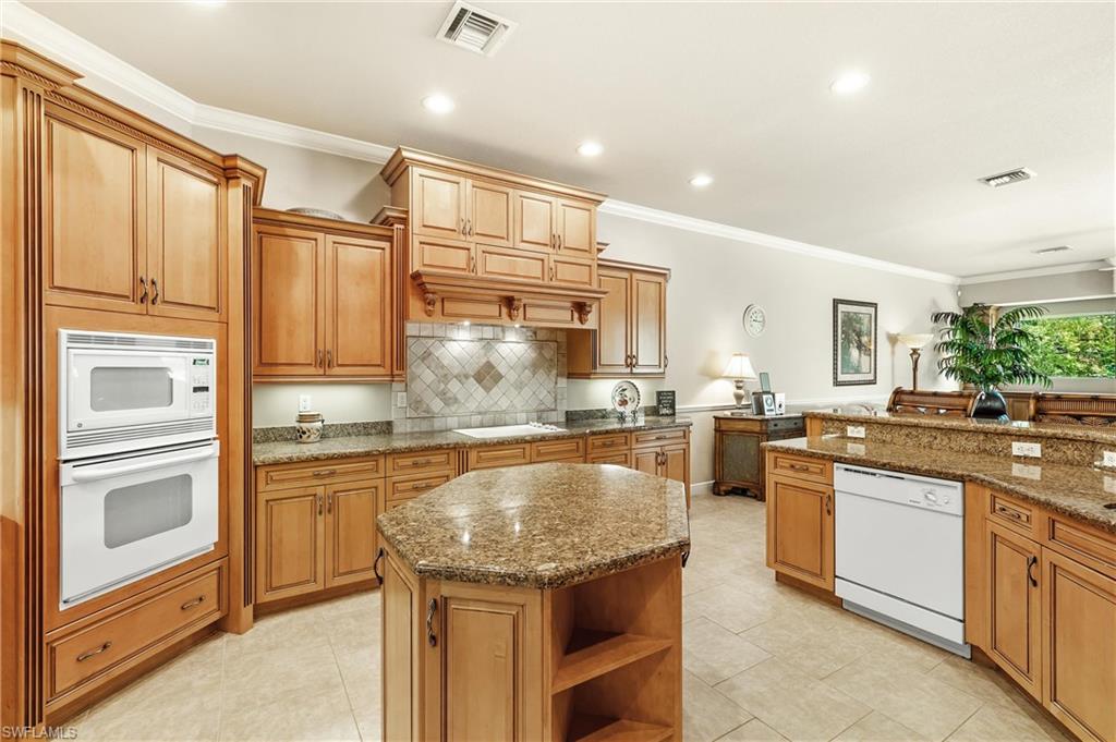 Kitchen featuring a built-in oven and microwave combination, an island with countertop seating, recessed lighting, and a tile backsplash