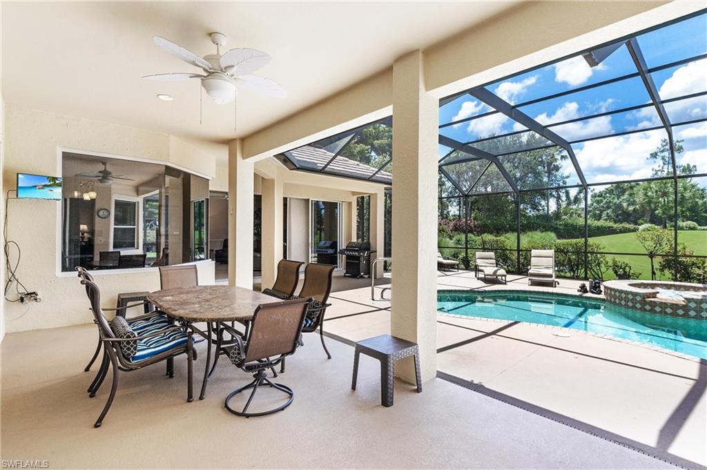 Expansive screened lanai featuring an in-ground pool, spa with tiled surround, and ceiling fan