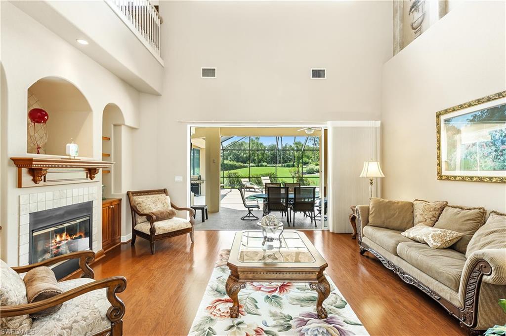 Two-story living area featuring wood-finish flooring and a fireplace with a tiled surround and wood mantel