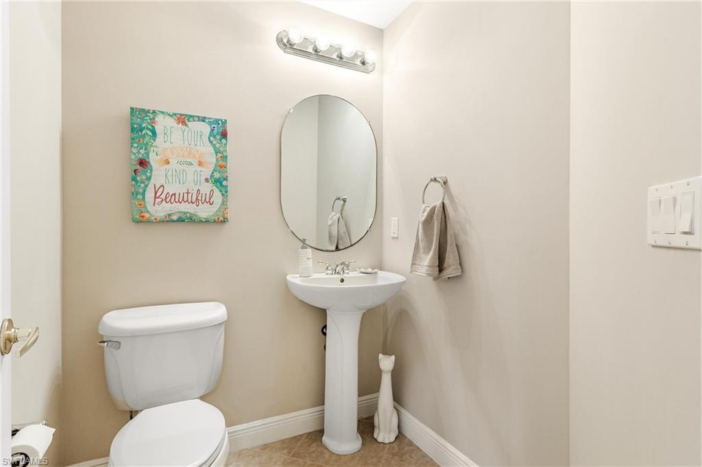 Half Bathroom on first floor with Pedestal sink with an oval mirror and a five-bulb vanity light fixture