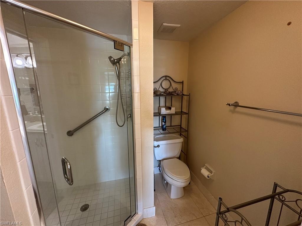 Glass-enclosed shower featuring a handheld showerhead, grab bar, and white tile surround