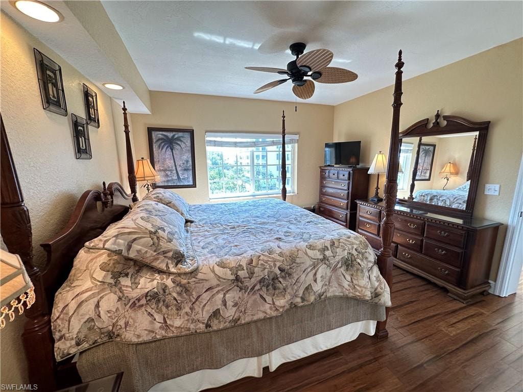 Spacious bedroom featuring wood-finish flooring, recessed lighting, a ceiling fan, and a wide window with horizontal blinds