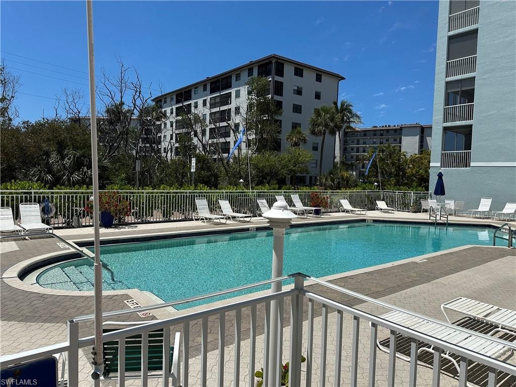 Resort-style pool area featuring a rectangular pool with curved entry steps, paver decking, and a surrounding white metal fence