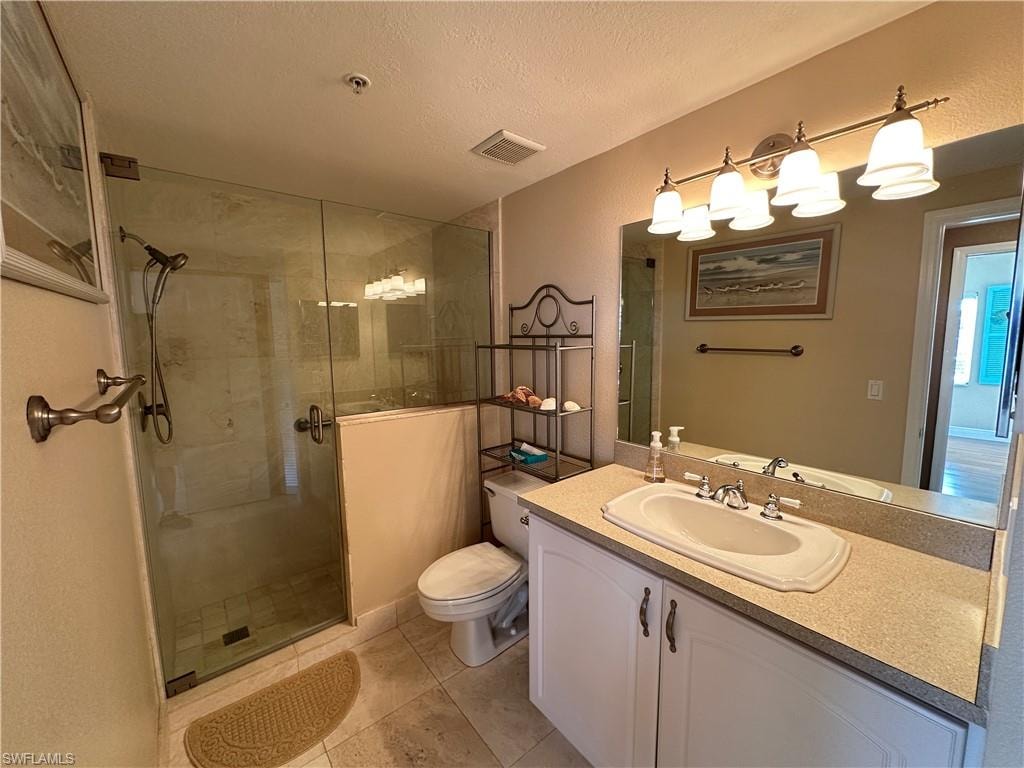 Bathroom featuring a glass-enclosed shower, single vanity with integrated sink, stone-finish countertop, and decorative wall lighting