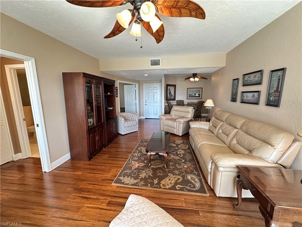 Open-concept living area featuring wood-finish flooring, a decorative ceiling fan, and neutral wall tones
