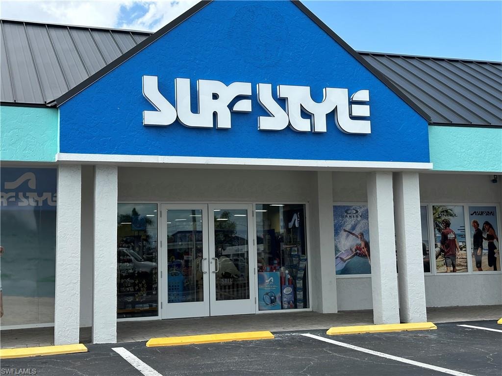 Commercial storefront featuring prominent signage, a metal roof, and a vibrant blue stucco facade