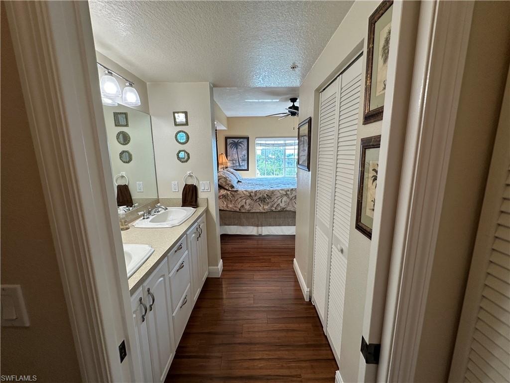 Dual vanity with integrated sinks and white cabinetry, complemented by dark wood-finish flooring