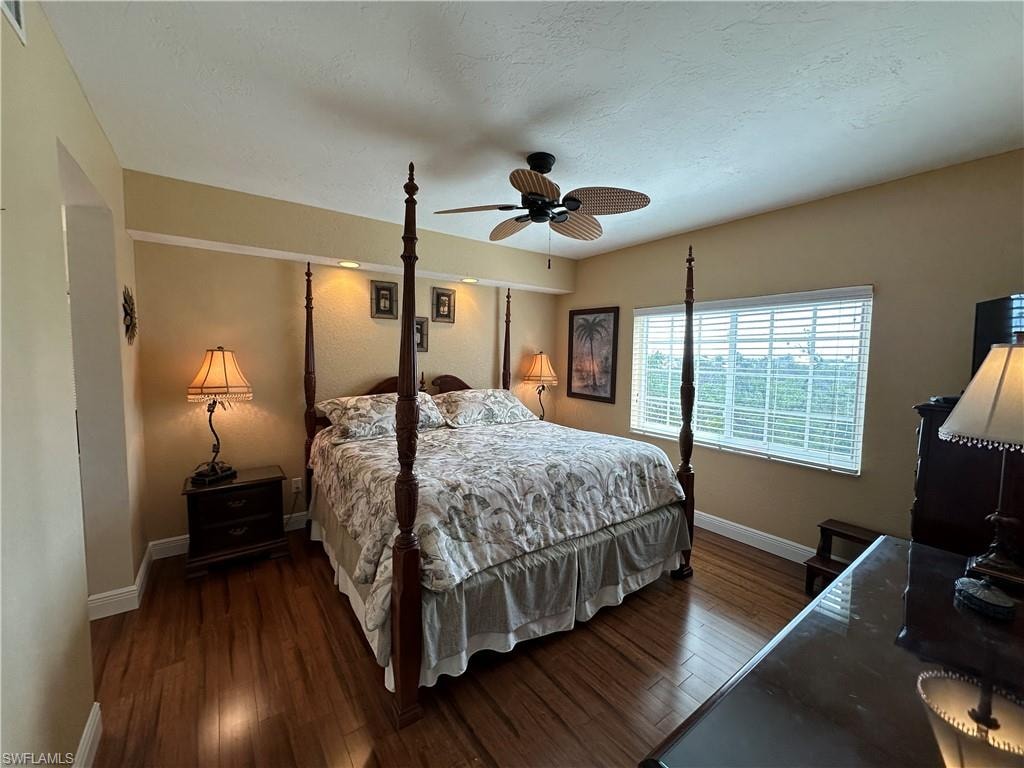 Spacious room featuring wood-finish flooring, a ceiling fan, and a large window with horizontal blinds