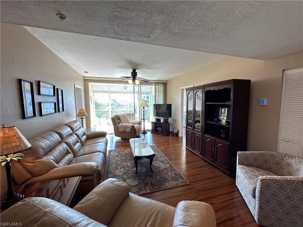 Spacious living area featuring wood-finish flooring, a ceiling fan, and access to an outdoor patio with white railings
