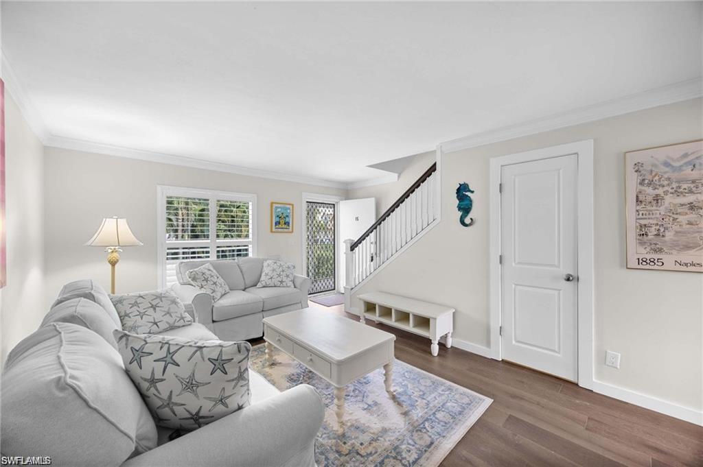 Open living area with wood-look flooring, plantation shutters, and staircase access in this Naples Florida residence.