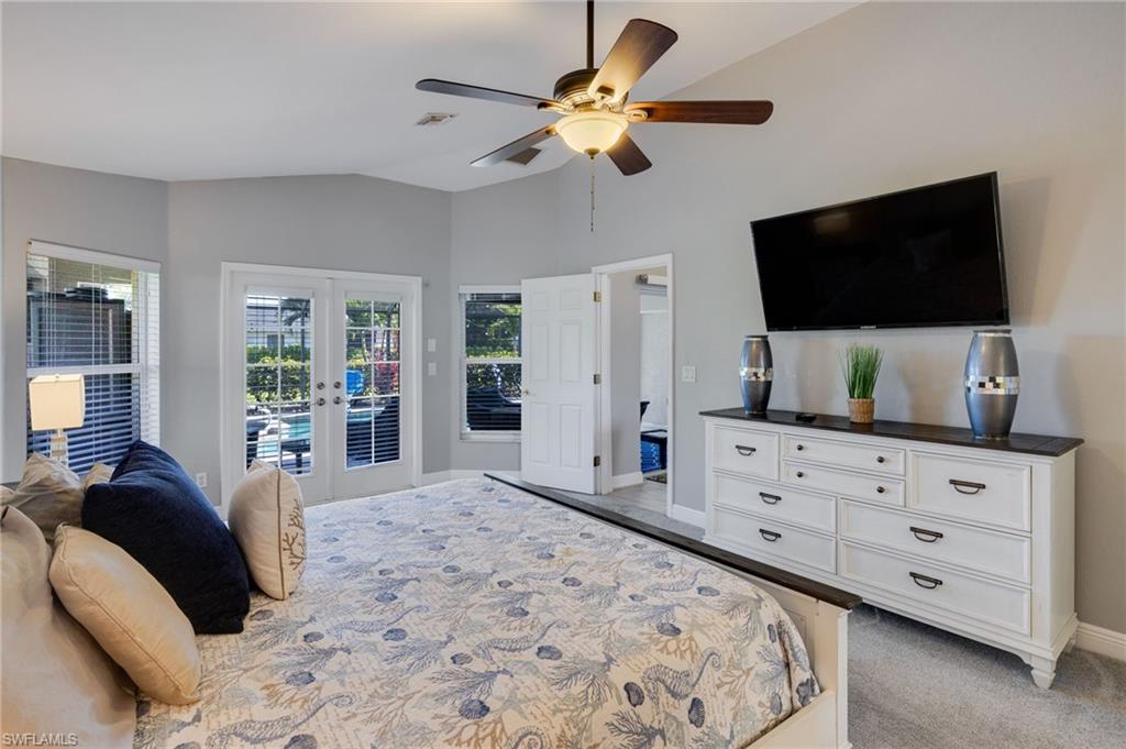 Spacious room featuring vaulted ceilings, a ceiling fan with integrated lighting, dual French doors, and an additional window
