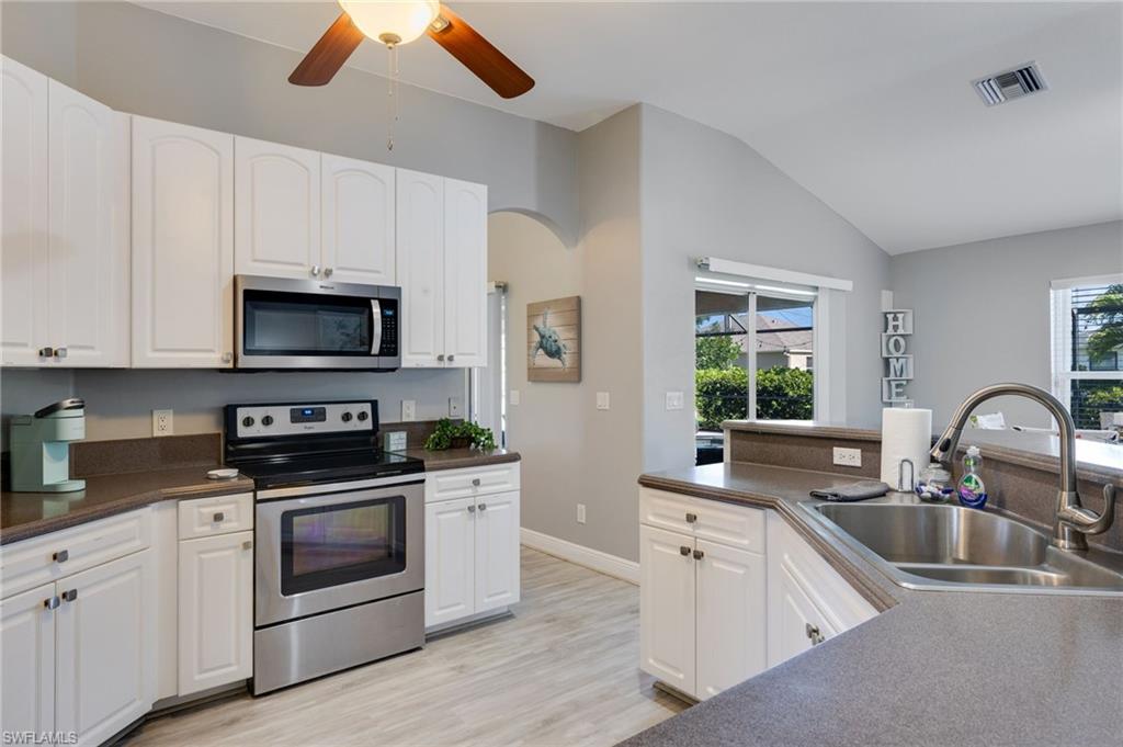 Kitchen featuring white cabinetry, stainless steel appliances, a double basin sink, and wood-finish flooring