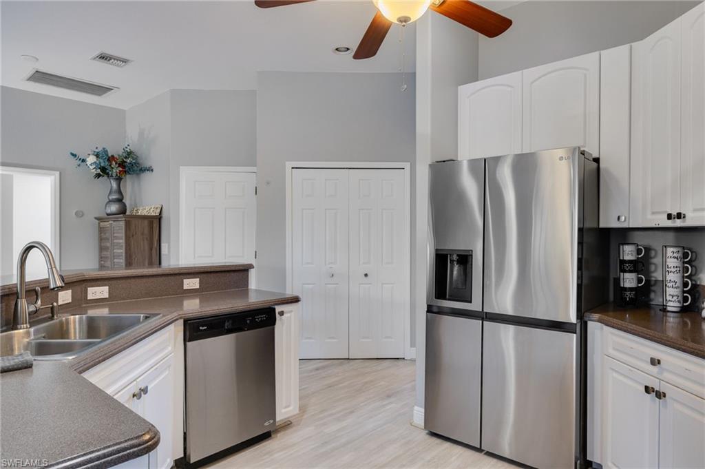 Kitchen featuring white cabinetry, stainless steel appliances, a double basin sink with a high-arc faucet, and wood-finish flooring