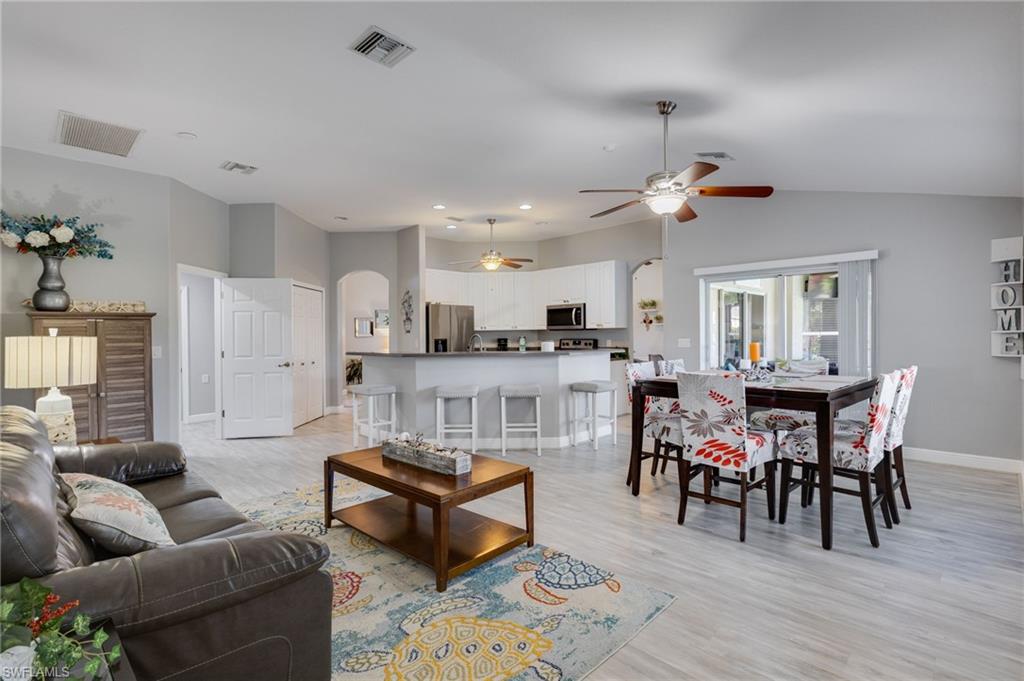 Open-concept living space featuring light wood-finish flooring, vaulted ceilings, and a neutral color palette