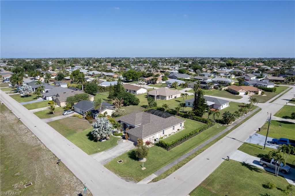 Aerial neighborhood perspective showcasing residential properties with varied rooflines and a mix of mature and nascent landscaping