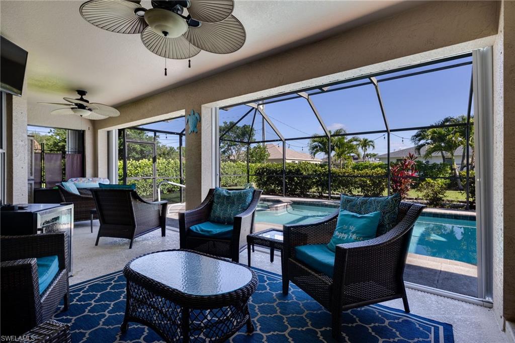 Screened-in patio with concrete flooring and direct pool access, featuring two installed ceiling fans and string lighting over the pool area