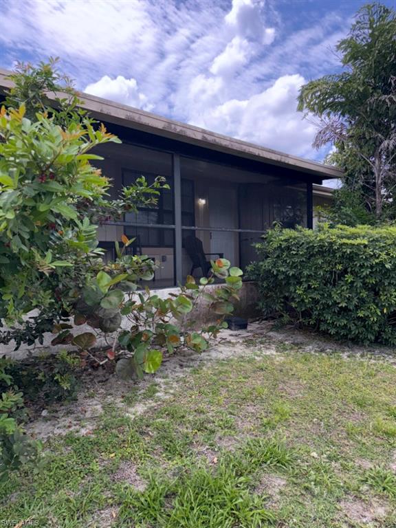 Screened patio with a covered overhang, surrounded by mature landscaping and a grassy area