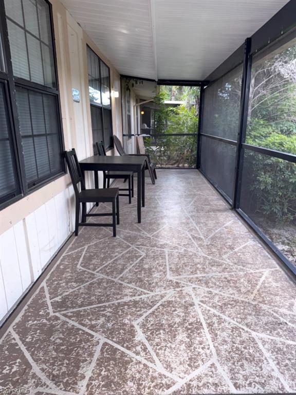 Screened porch featuring a geometrically patterned concrete floor, white tongue-and-groove ceiling, and exterior wall paneling with multiple windows
