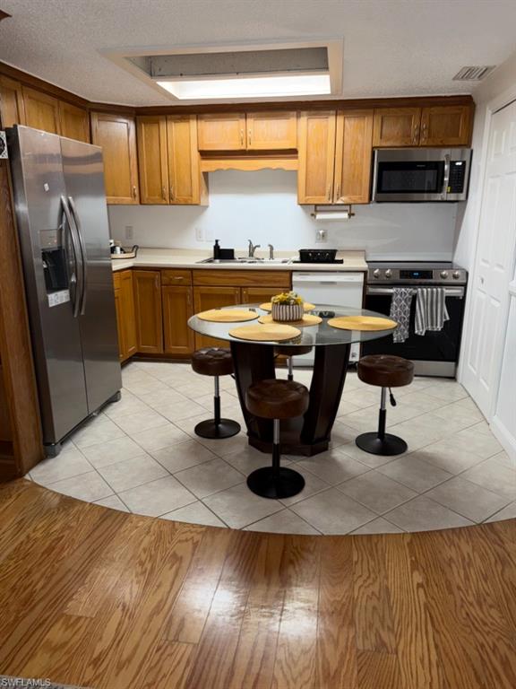 Kitchen featuring wood cabinetry, stainless steel appliances, and a skylight