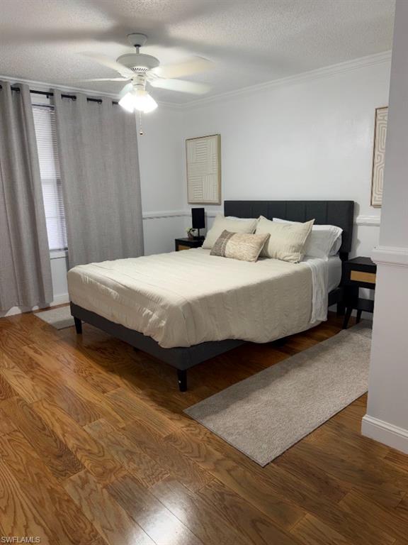 Spacious room featuring wood-finish flooring, white walls, and a ceiling fan with integrated lighting