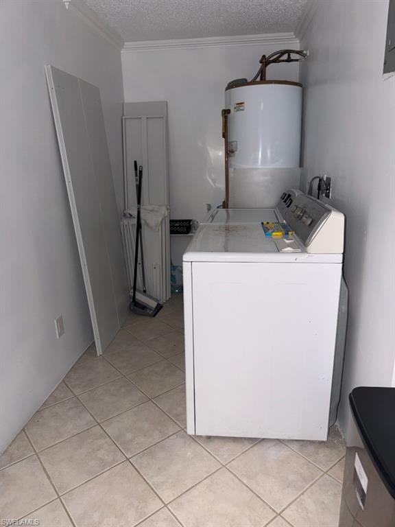Laundry area featuring a top-load washing machine, a water heater, and light-toned tile flooring