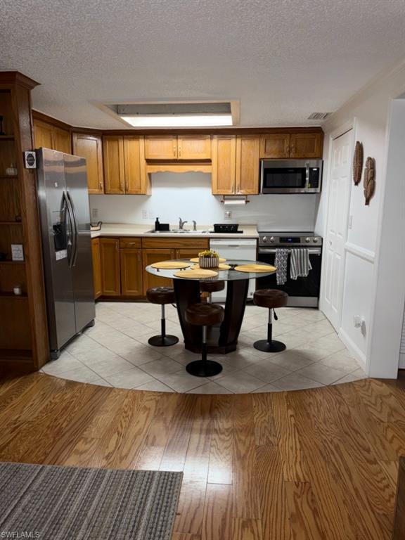 Kitchen featuring wood cabinetry, stainless steel appliances, and a tile floor