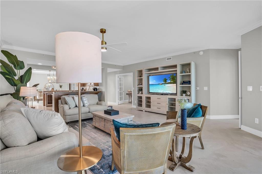Living room featuring ceiling fan with notable chandelier, crown molding, and light colored carpet