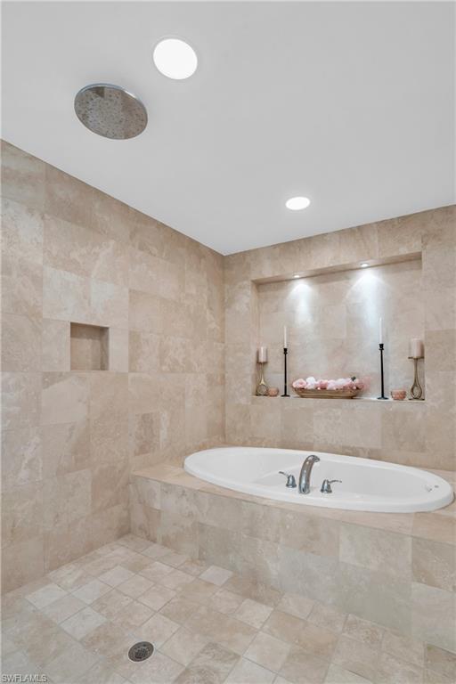 Bathroom featuring tile floors, shower with separate bathtub, and tile walls