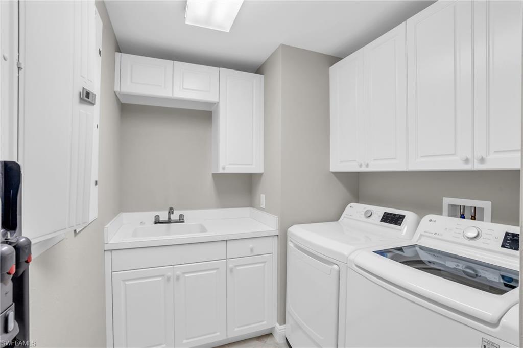 Laundry room with hookup for a washing machine, sink, separate washer and dryer, and cabinets