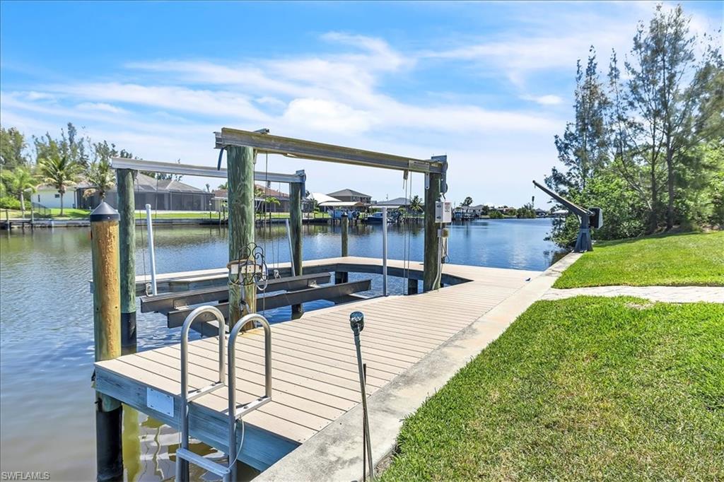 Waterfront property featuring a private boat dock with an installed boat lift, direct canal access, a boat davit, and a marine ladder