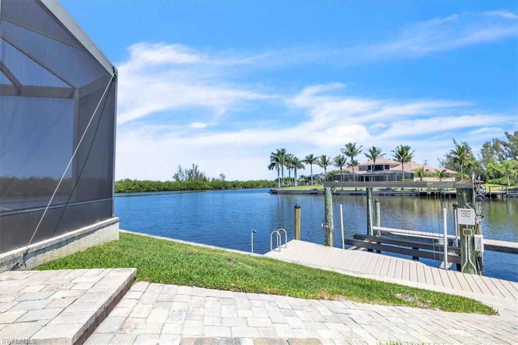Waterfront property featuring a screened lanai, paver patio, a private boat lift, and a timber dock