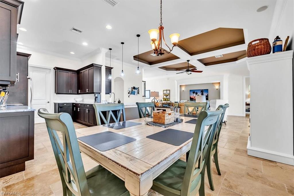 Open-concept kitchen and dining area featuring stone-finish flooring, dark wood cabinetry, and recessed lighting
