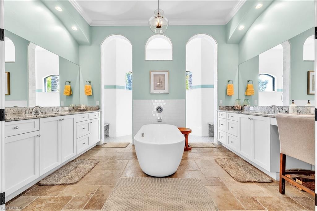 Freestanding soaking tub centered on natural stone flooring