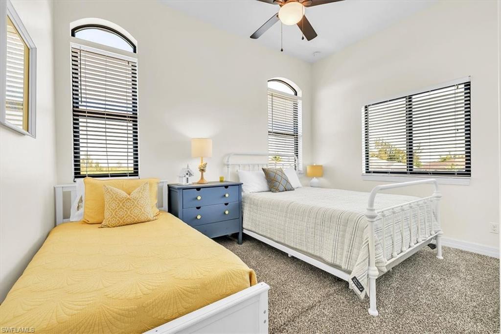 Carpeted room featuring a vaulted ceiling and a ceiling fan with light fixture