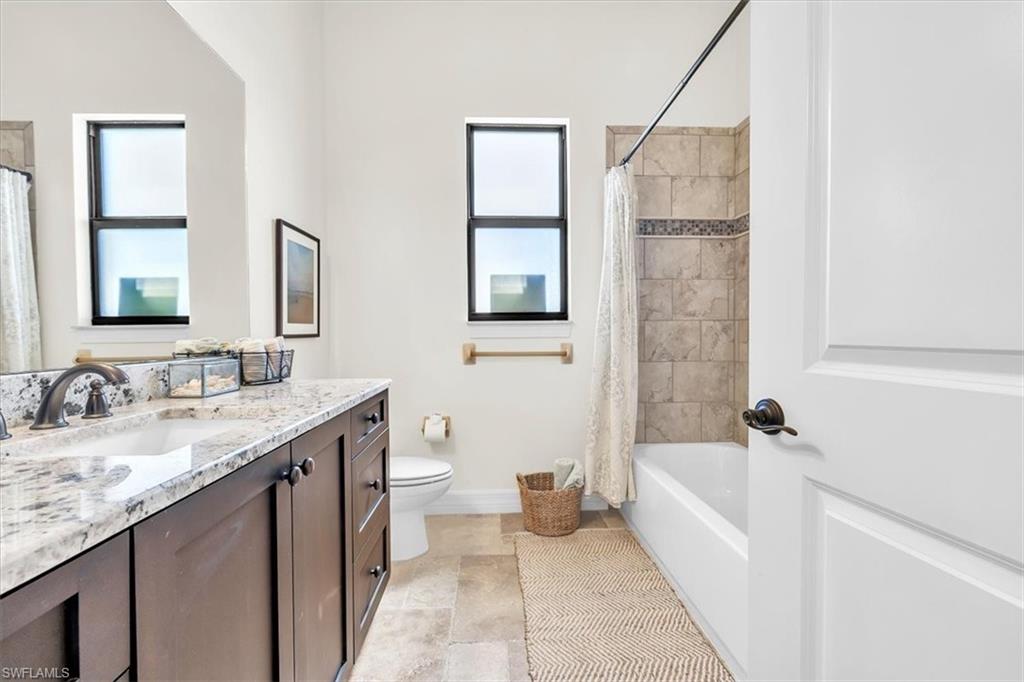 Bathroom featuring a single vanity with stone countertop, under-mount sink, and dark wood cabinetry