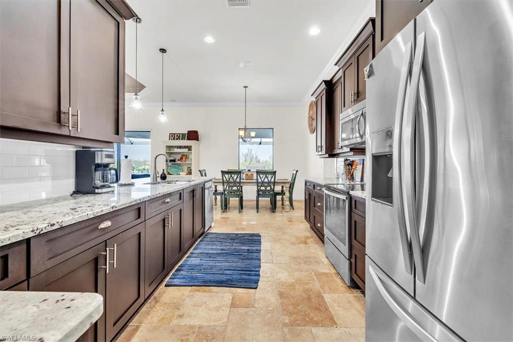 Galley kitchen featuring dark wood cabinetry, light-toned granite countertops, and a subway tile backsplash