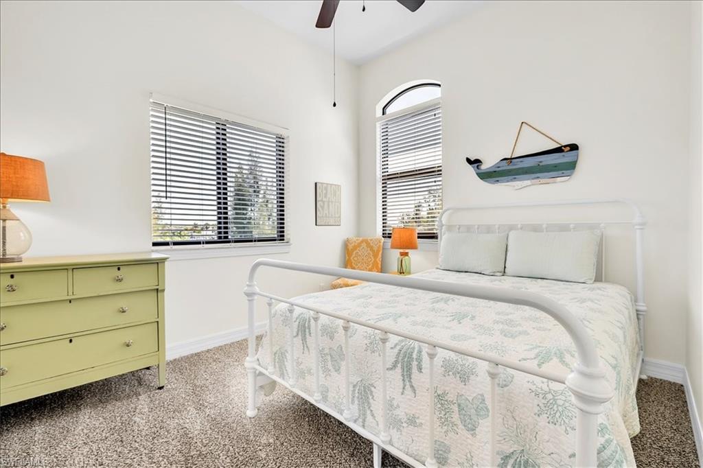 Carpeted room featuring white walls, a vaulted ceiling, and a ceiling fan