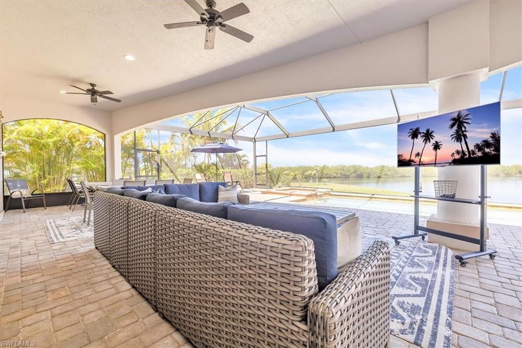 Expansive screened-in lanai featuring paver flooring, multiple ceiling fans, and arched openings