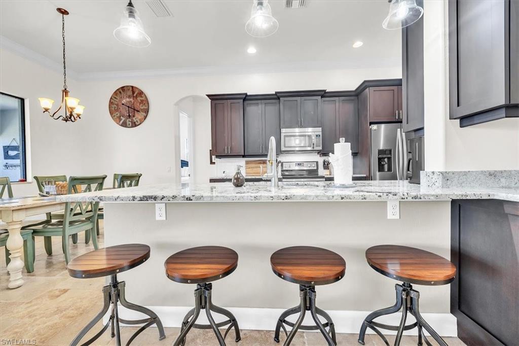 Kitchen featuring a peninsula with light speckled countertops, dark wood-finish cabinetry, stainless steel appliances, and recessed lighting