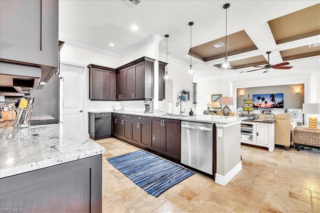 Modern kitchen featuring dark wood cabinetry, light speckled countertops, stainless steel appliances, and pendant lighting over the island
