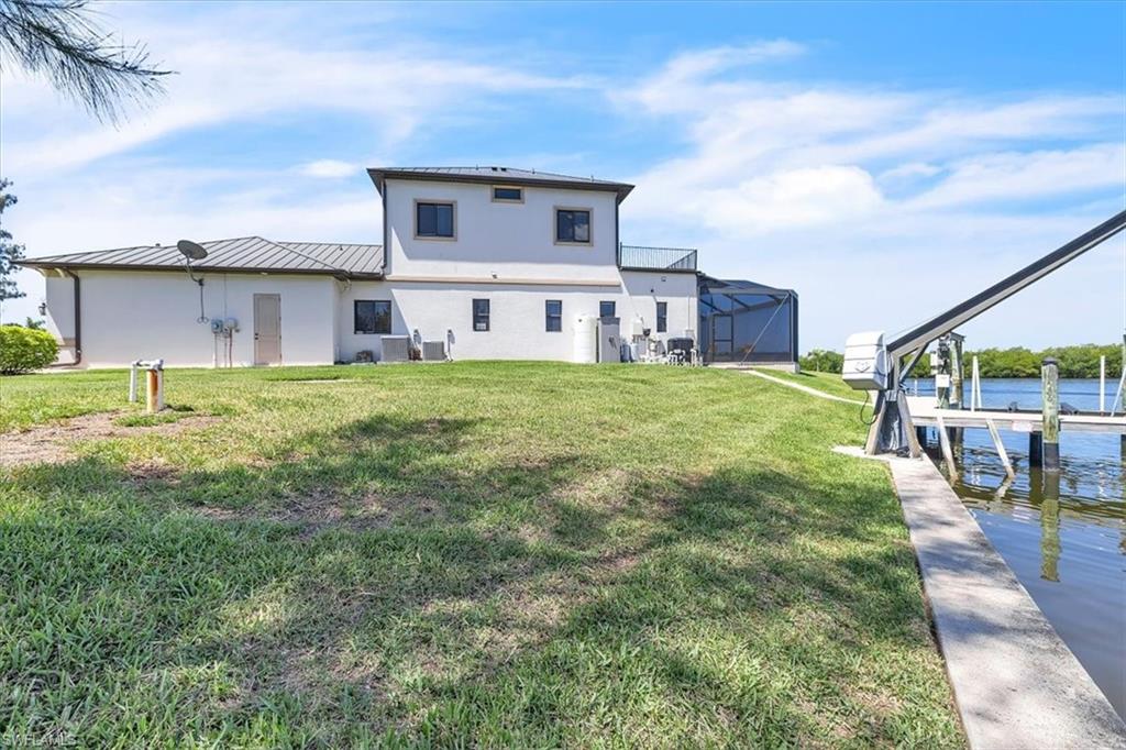 Waterfront property featuring a private dock with a boat lift, a screened lanai, and a two-story exterior with multiple windows