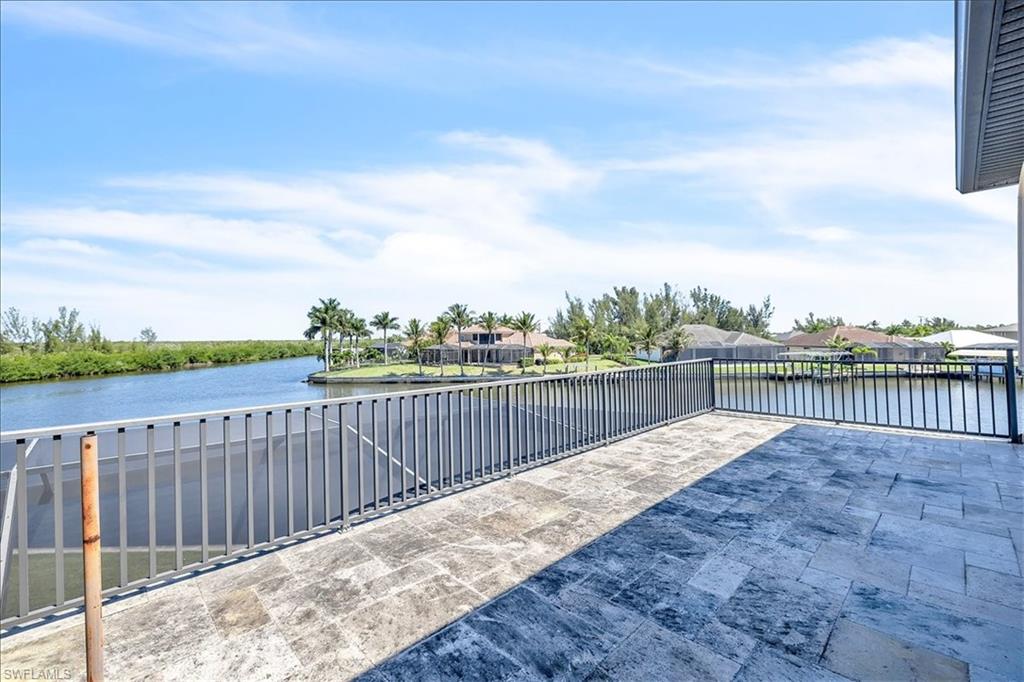 Expansive outdoor patio featuring large format tile flooring and a metal railing overlooking a wide canal
