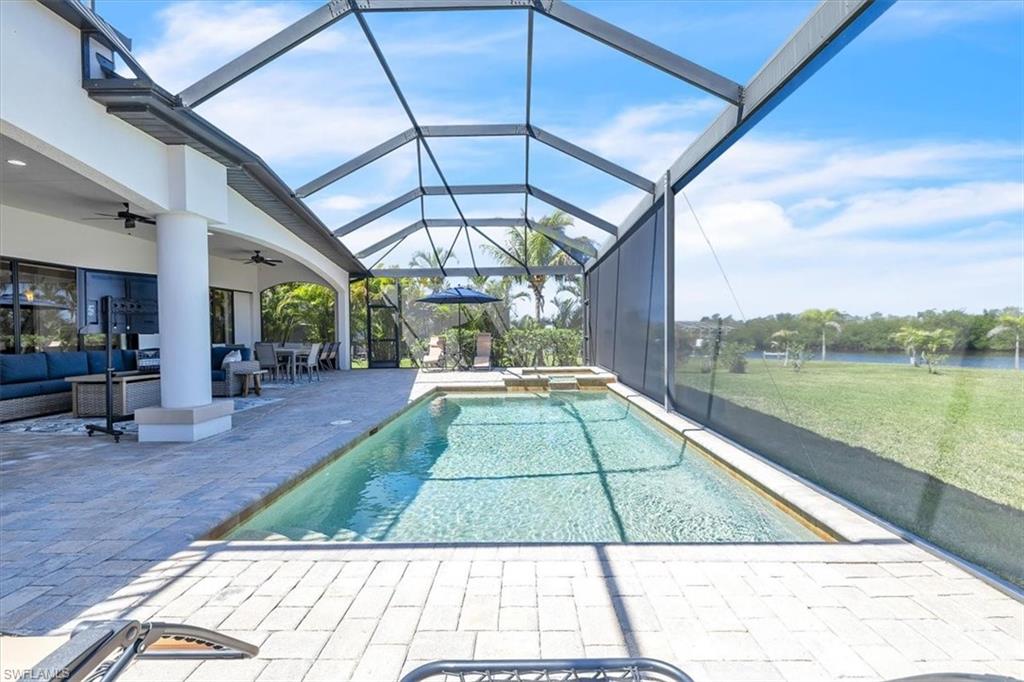 Screened lanai featuring a rectangular swimming pool, integrated spa, and expansive paver deck