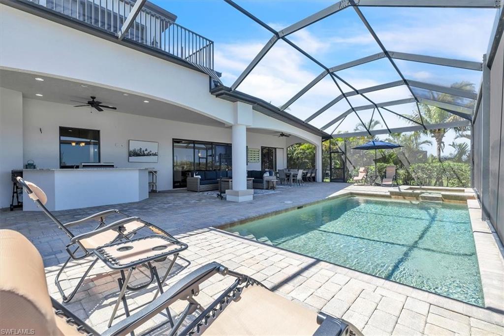 Screened lanai featuring a swimming pool, integrated spa, and paver decking