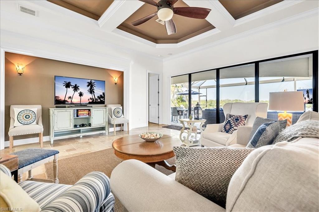 Living area featuring a tray ceiling with a ceiling fan, recessed wall niche with sconce lighting, and expansive glass sliding doors