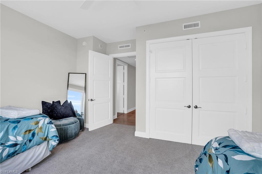 Carpeted bedroom with ceiling fan and a closet
