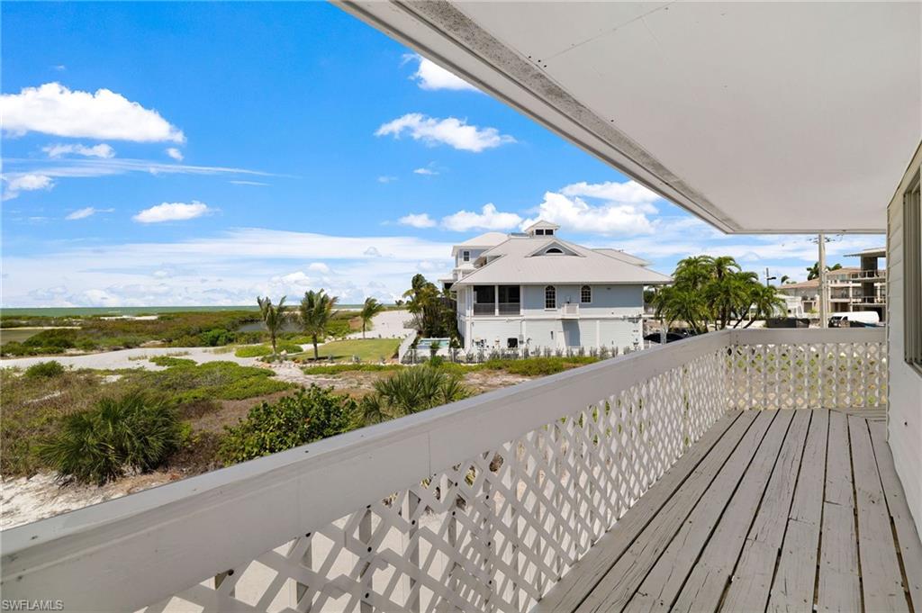 Outdoor balcony featuring a painted wood floor, white lattice railing, and an overhead awning - Virtually Edited Image