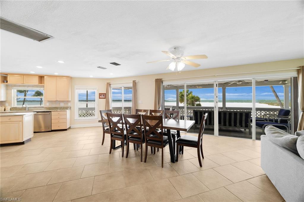 Open-concept living space featuring expansive sliding glass doors, large windows, recessed lighting, and tile flooring - Virtually Edited Image