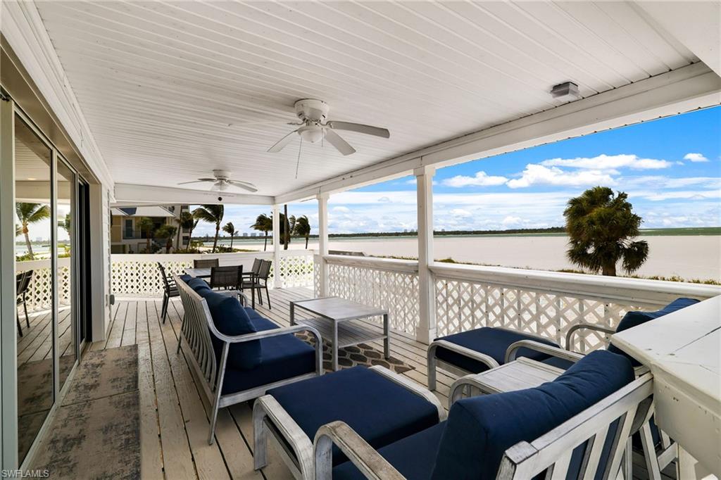 Expansive covered porch featuring white wood-finish flooring, a white wood-paneled ceiling, and multiple ceiling fans - Virtually Edited Image