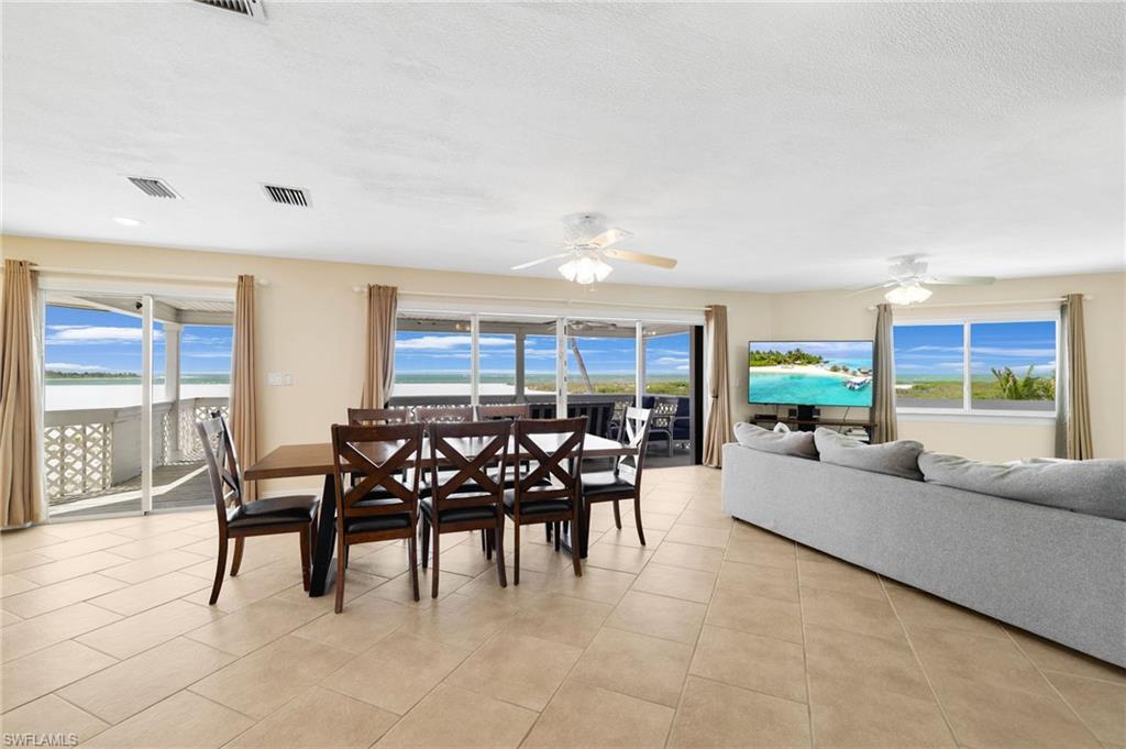 Open-concept living space with light-toned tile flooring throughout - Virtually Edited Image